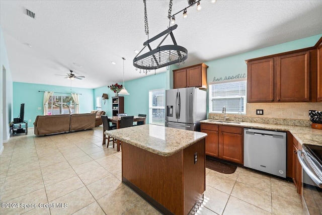 kitchen featuring appliances with stainless steel finishes, ceiling fan, sink, a center island, and hanging light fixtures