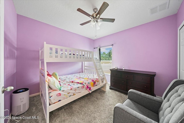 carpeted bedroom featuring ceiling fan and a textured ceiling