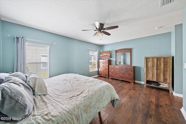 bedroom with a textured ceiling, ceiling fan, and dark wood-type flooring