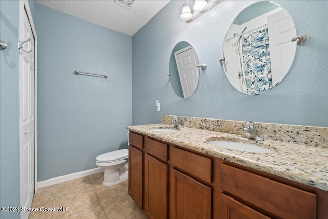 bathroom featuring vanity, a textured ceiling, toilet, and tile patterned flooring