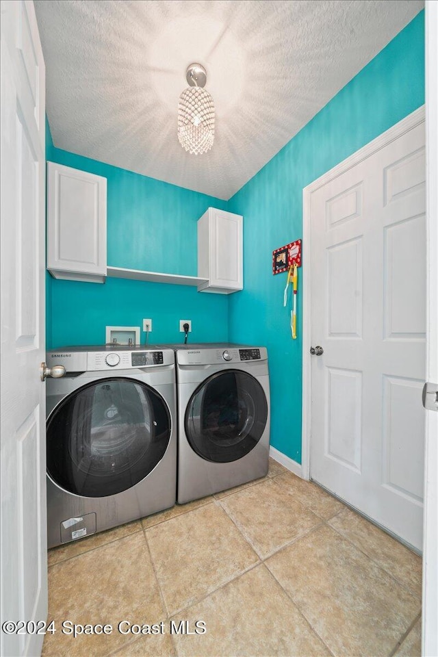 laundry room with light tile patterned flooring, cabinets, separate washer and dryer, and a textured ceiling