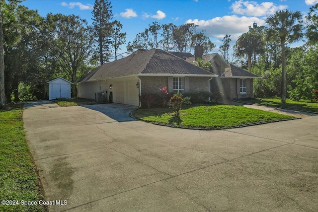 ranch-style home with a front yard, a garage, central AC unit, and a storage shed