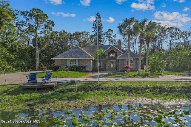 view of front of home with a front lawn and a water view