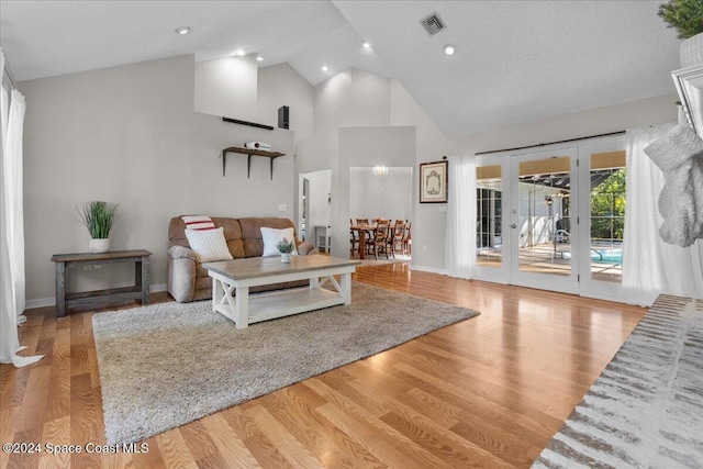 living room with french doors, high vaulted ceiling, a textured ceiling, and light wood-type flooring