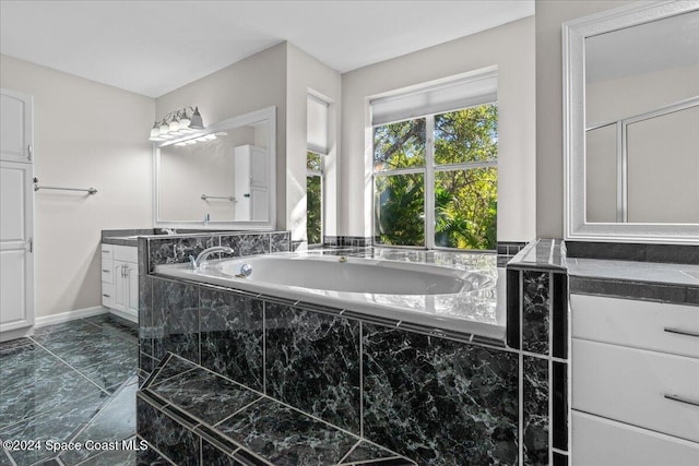 bathroom with tiled tub and vanity