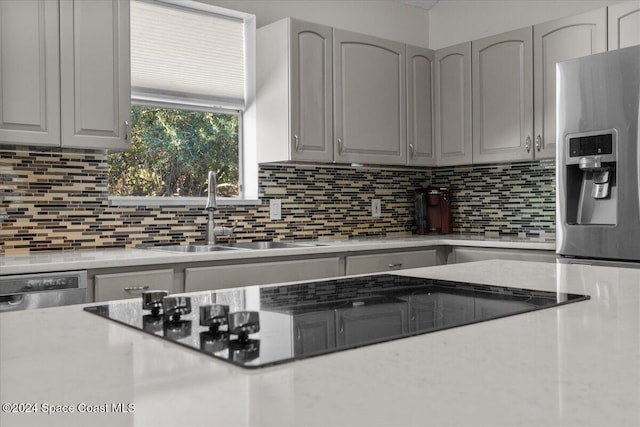 kitchen with decorative backsplash, black electric cooktop, gray cabinetry, and sink