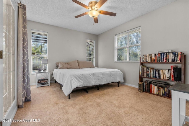 carpeted bedroom with a textured ceiling, multiple windows, and ceiling fan