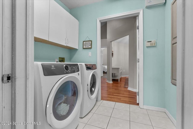 laundry room featuring washer and clothes dryer, light tile patterned floors, and cabinets