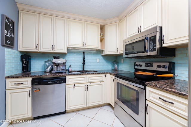 kitchen with light tile patterned flooring, backsplash, stainless steel appliances, and sink