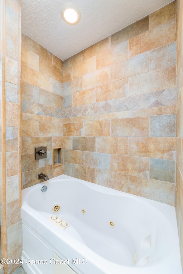 bathroom featuring tile walls, a bathtub, and a textured ceiling