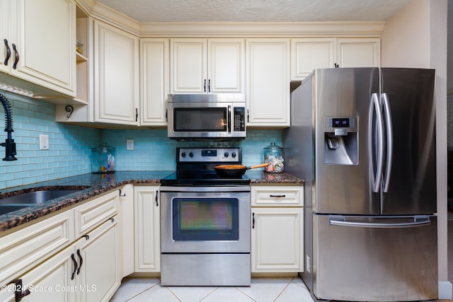 kitchen featuring dark stone countertops, light tile patterned floors, stainless steel appliances, and tasteful backsplash