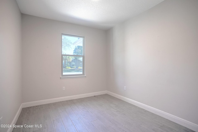 empty room with light hardwood / wood-style flooring and a textured ceiling