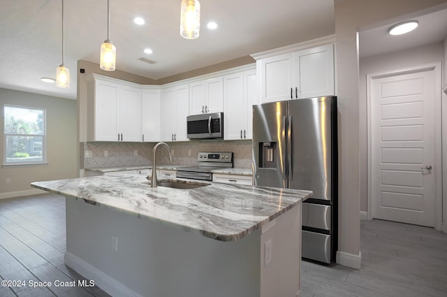 kitchen featuring decorative light fixtures, light stone counters, white cabinetry, and stainless steel appliances