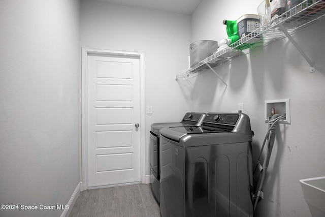 laundry room with sink, light hardwood / wood-style floors, and independent washer and dryer