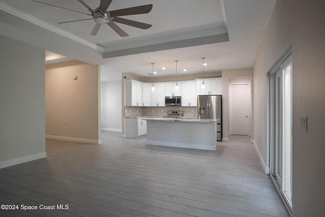 kitchen with light wood-type flooring, decorative light fixtures, a kitchen island, white cabinetry, and stainless steel appliances