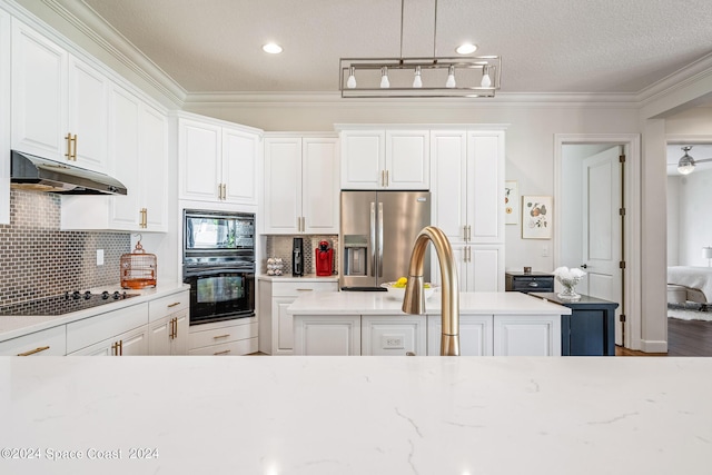 kitchen featuring decorative backsplash, a kitchen island, black appliances, pendant lighting, and white cabinetry