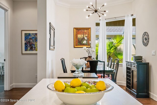 dining space with dark hardwood / wood-style flooring, ornamental molding, and an inviting chandelier