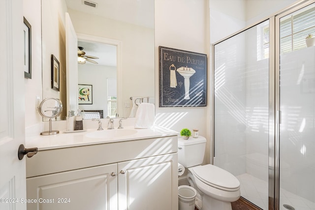 bathroom featuring vanity, a shower with door, toilet, and ceiling fan