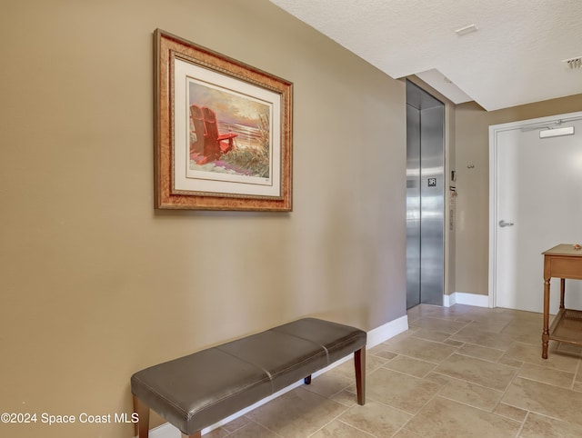 corridor featuring elevator and a textured ceiling