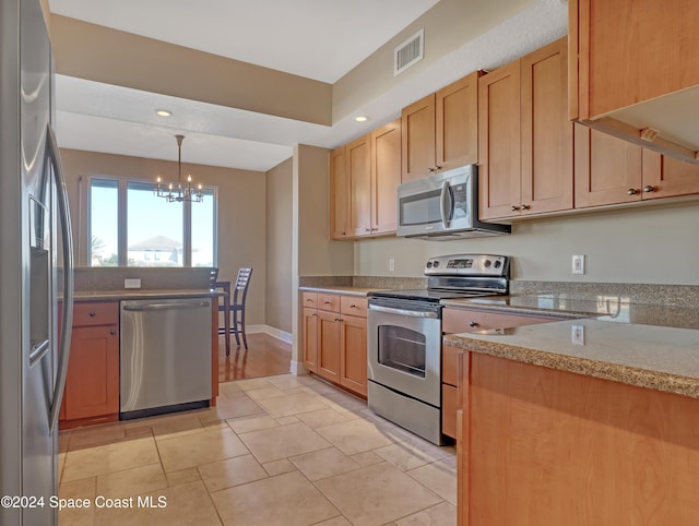 kitchen with pendant lighting, light stone countertops, stainless steel appliances, and an inviting chandelier