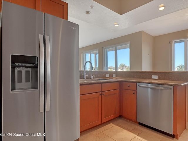 kitchen with sink, light tile patterned flooring, stainless steel appliances, and a textured ceiling