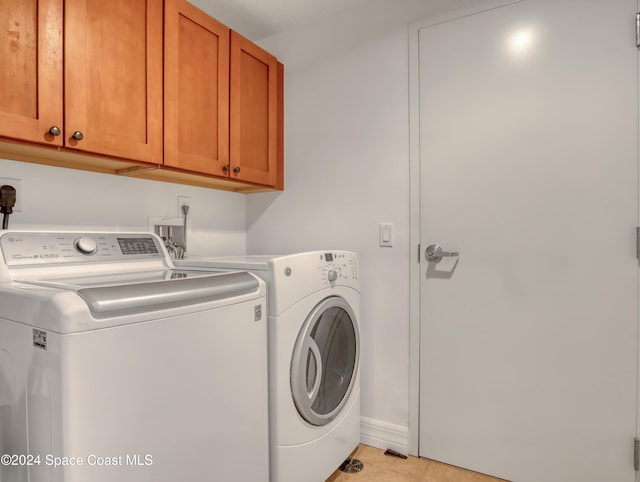 laundry room featuring separate washer and dryer, light tile patterned floors, and cabinets