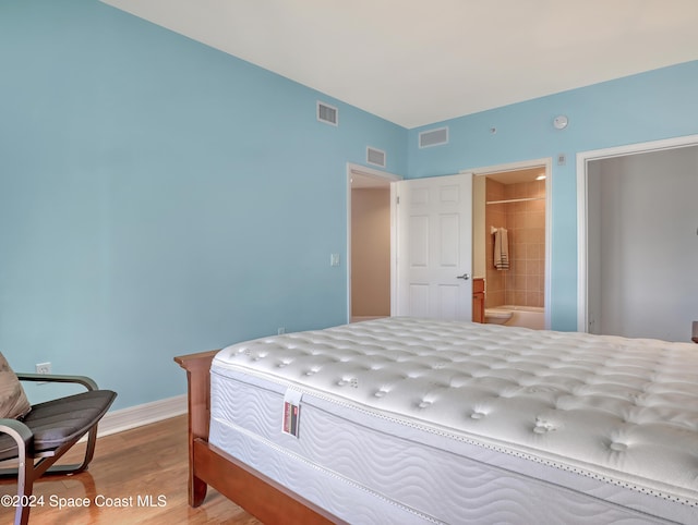 bedroom with light wood-type flooring and connected bathroom