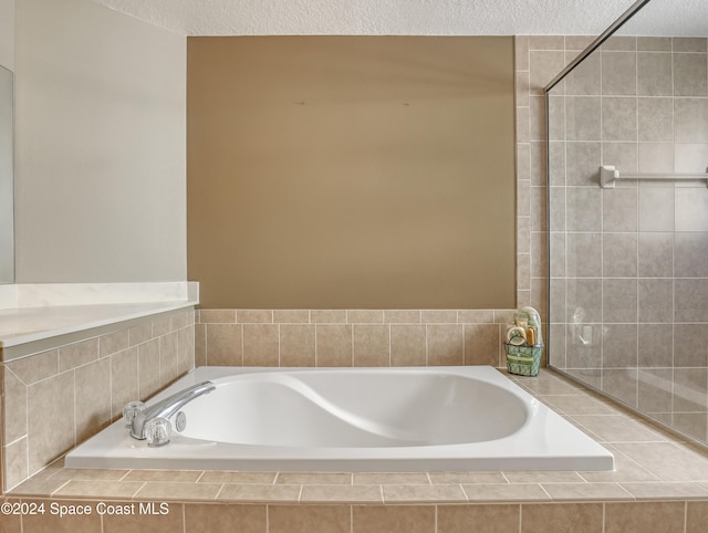 bathroom featuring a textured ceiling and tiled bath