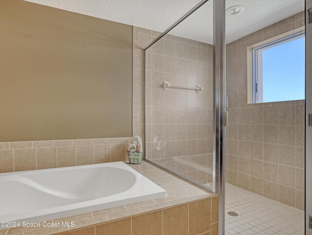 bathroom with a textured ceiling and independent shower and bath