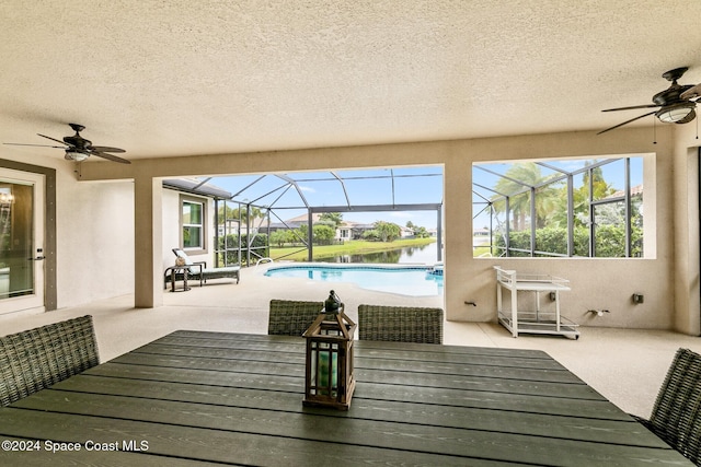 view of patio / terrace with a water view, ceiling fan, and glass enclosure