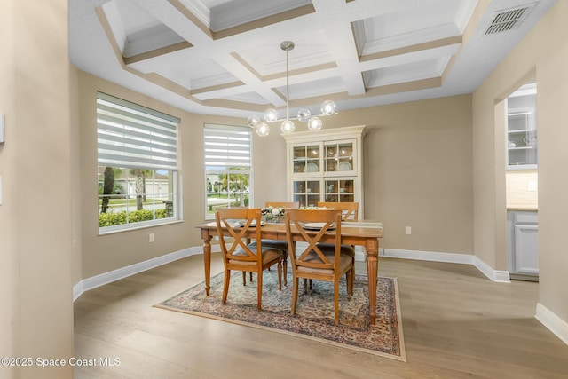 dining space with coffered ceiling, an inviting chandelier, crown molding, beamed ceiling, and light hardwood / wood-style floors