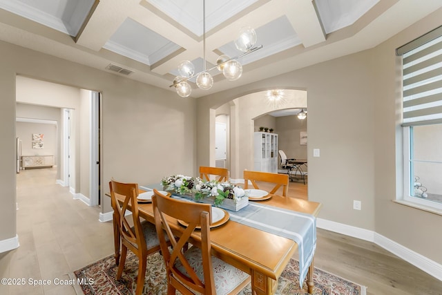 dining space with beamed ceiling, crown molding, coffered ceiling, and light hardwood / wood-style floors