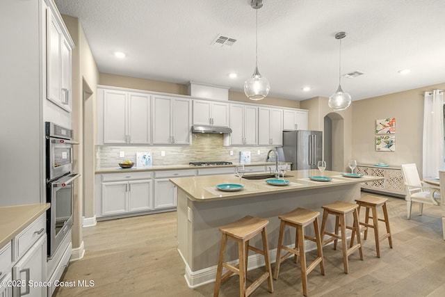 kitchen with white cabinetry, appliances with stainless steel finishes, sink, and a kitchen island with sink