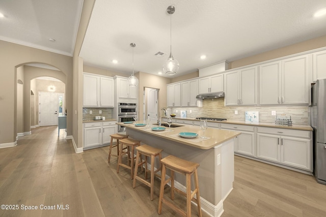 kitchen with stainless steel appliances, hanging light fixtures, sink, and white cabinets