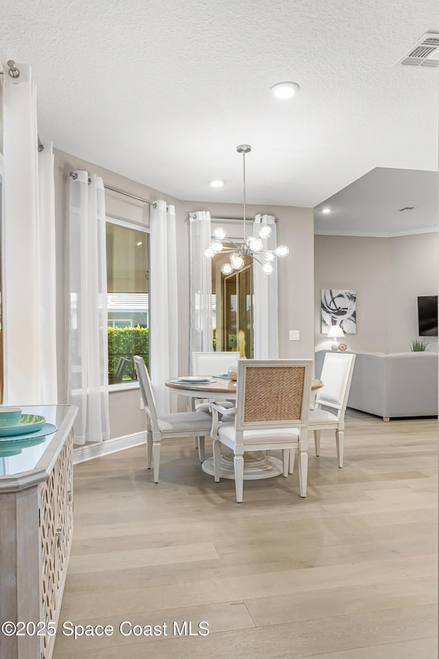 dining room featuring a notable chandelier, a textured ceiling, and light wood-type flooring