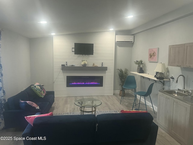 living room featuring a wall mounted AC, light wood-type flooring, a glass covered fireplace, and recessed lighting