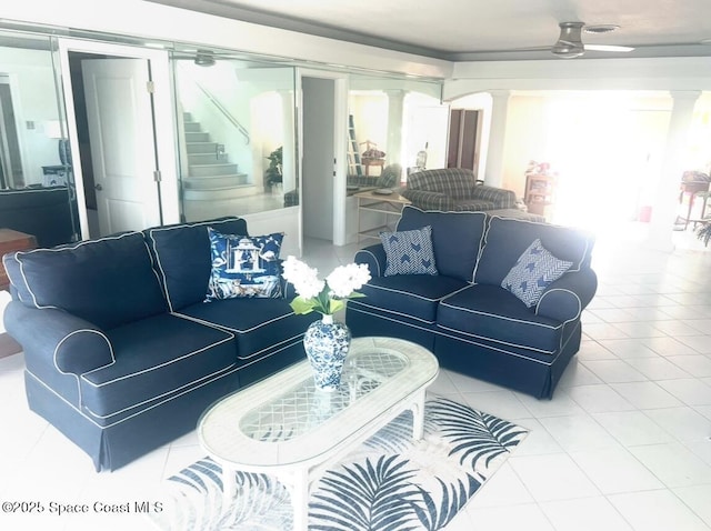 tiled living area with decorative columns, stairs, plenty of natural light, and a ceiling fan