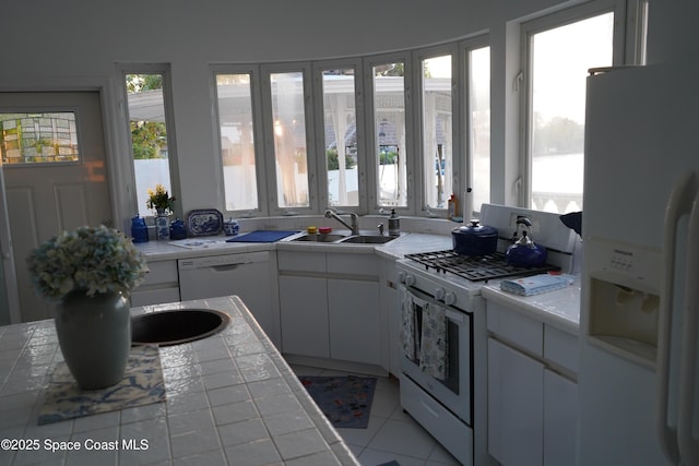 kitchen featuring white appliances, a sink, tile countertops, and white cabinets