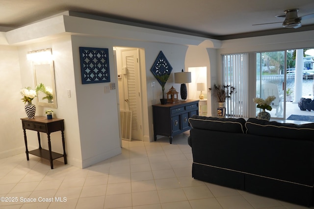 living area with baseboards, light tile patterned floors, and ceiling fan