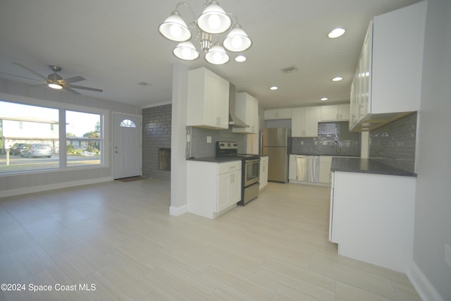 kitchen with ceiling fan with notable chandelier, stainless steel appliances, white cabinetry, and backsplash