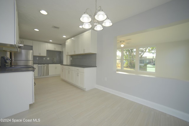 kitchen with appliances with stainless steel finishes, backsplash, ceiling fan with notable chandelier, decorative light fixtures, and white cabinets