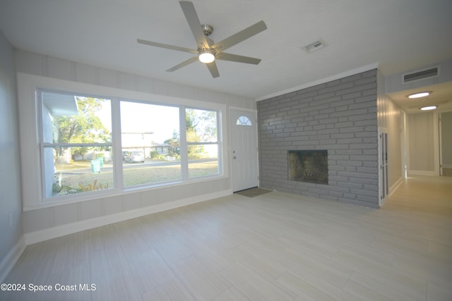 unfurnished living room featuring ceiling fan and a brick fireplace