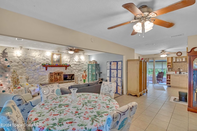 tiled bedroom with a stone fireplace, ceiling fan, sink, and a textured ceiling