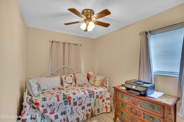 bedroom with ceiling fan, light hardwood / wood-style floors, and a textured ceiling