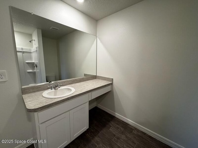 bathroom with a textured ceiling, vanity, and toilet