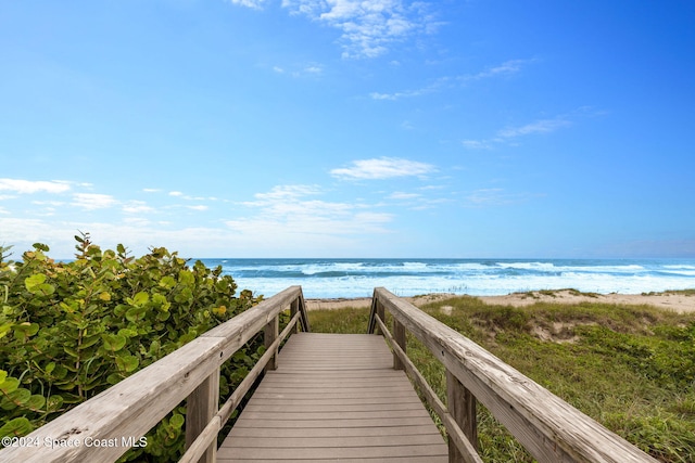 view of property's community with a water view and a beach view