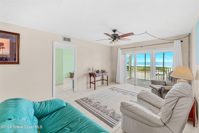 living room with ceiling fan, light tile patterned flooring, and a textured ceiling