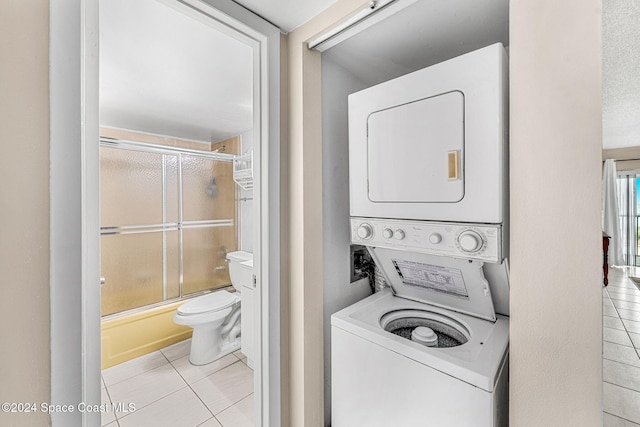 laundry area featuring light tile patterned floors and stacked washing maching and dryer