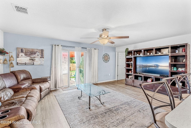 living room with ceiling fan, light hardwood / wood-style floors, and a textured ceiling