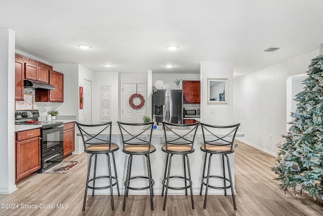 kitchen featuring a kitchen breakfast bar, light hardwood / wood-style flooring, a kitchen island, and appliances with stainless steel finishes